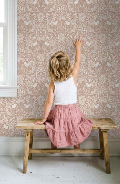 Vliestapete mit floralem Damastmuster und Vögeln an einer Wand hinter einer rustikalen Holzbank mit einem Kind.
