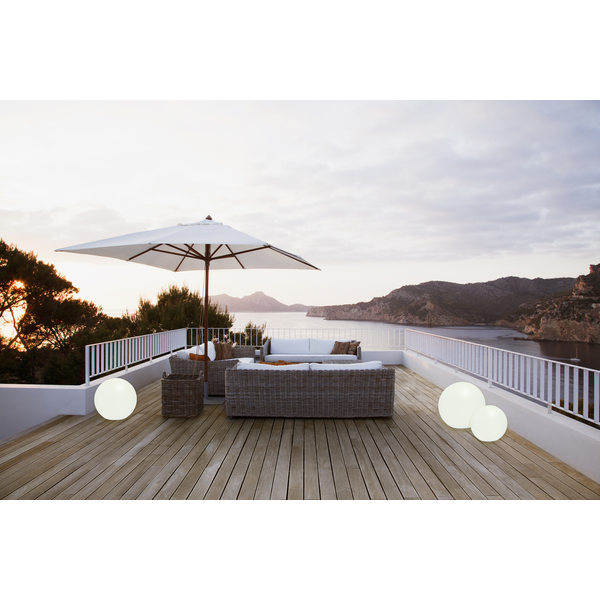 Terrasse mit Rattansitzgruppe, Sonnenschirm und Dekokugeln mit Meerblick