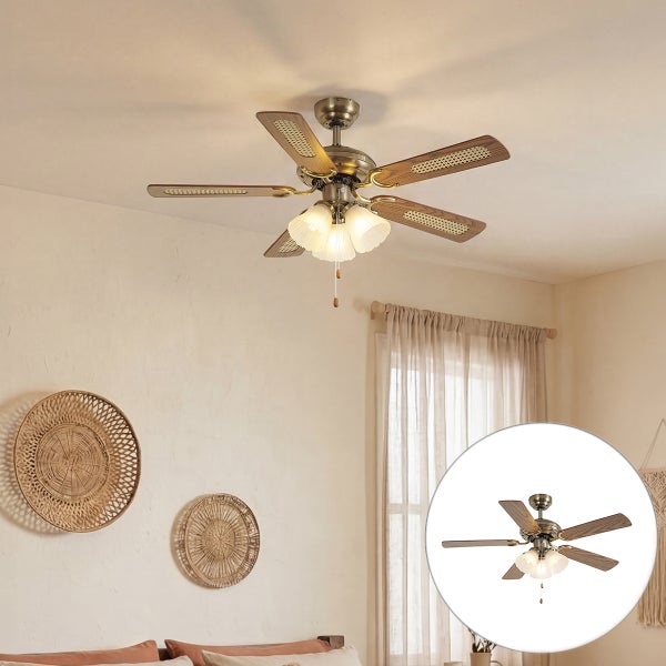 Deckenventilator mit Beleuchtung im klassischen Design mit fuenf Luefterfluegeln aus Holzgeflecht und drei Lampenschirmen in einem Wohnraum.