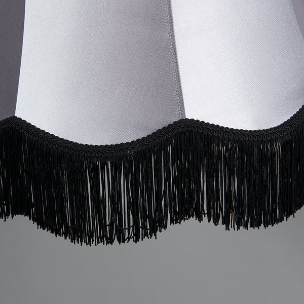 Detailansicht eines gestreiften Textilschirmes mit schwarzen Fransen an der gewellten Unterkante.