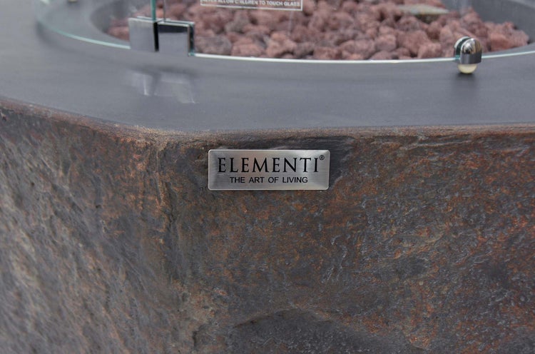 Elementi Logo auf einer Feuerstelle mit Steinstruktur, Lavasteinen und Glasschutz.