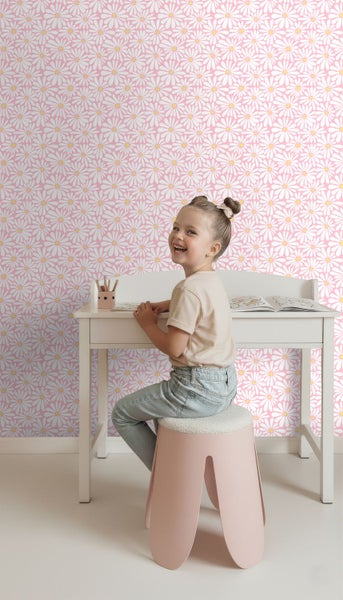 Helles Kinderzimmer mit rosa Gänseblümchen Tapete, weißem Schreibtisch und rosa Hocker