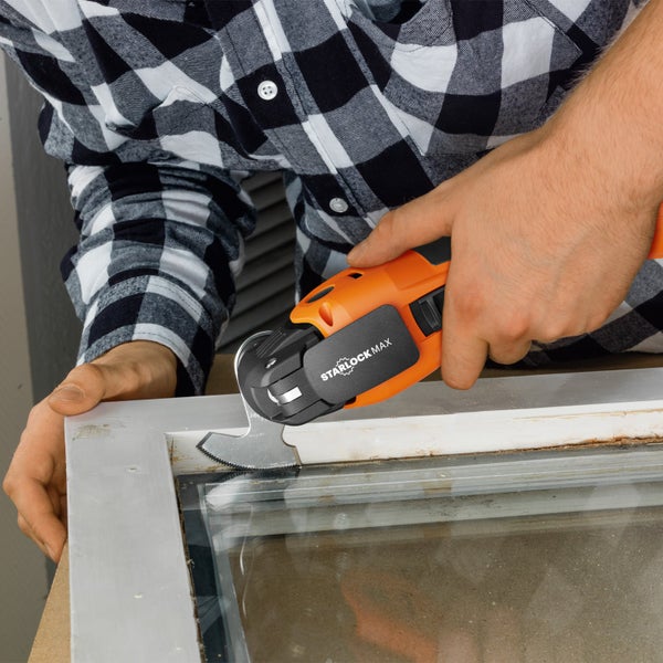 Mann verwendet Multifunktionswerkzeug zum Bearbeiten eines Fensterrahmens.