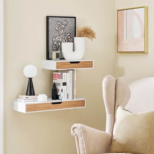 Wohnzimmerwand mit zwei weißen Wandregalen mit Schubladen und Dekorationsgegenständen.