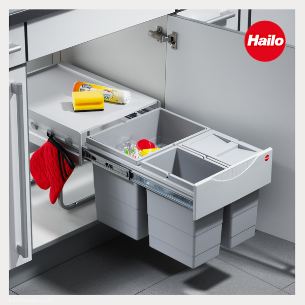 Hailo Logo. Organisiertes Abfalltrennsystem mit drei Eimern und Auszugssystem im Küchenunterschrank, inklusive Ablage für Reinigungszubehör.
