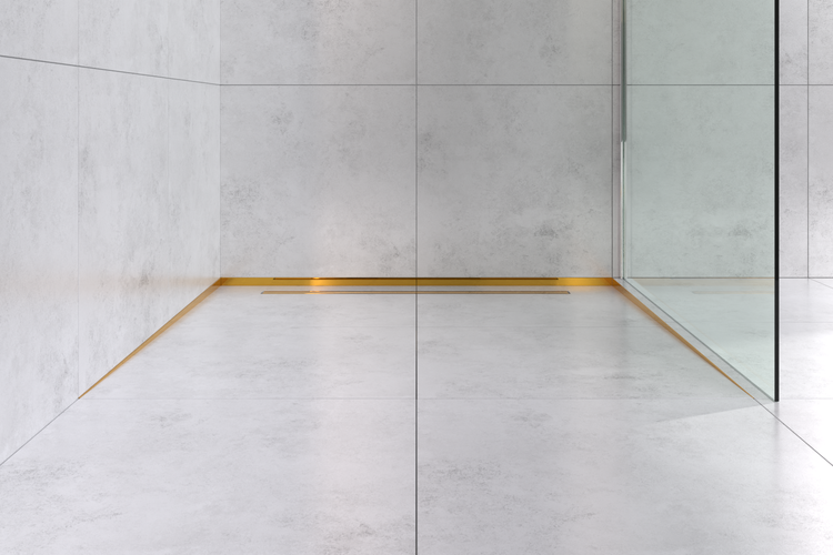 Moderne begehbare Dusche mit hellgrauen Fliesen in Betonoptik und einer goldfarbenen Duschrinne an der Wand.