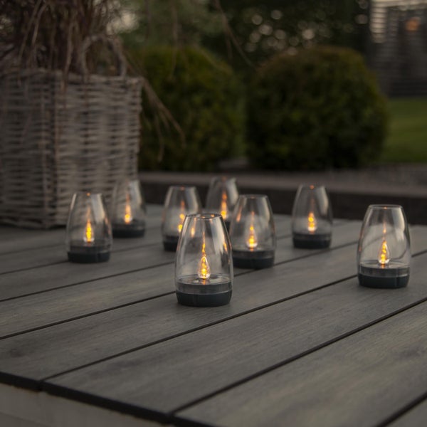 Mehrere kabellose Windlichter auf einem Holztisch für eine gemütliche Atmosphäre im Garten.