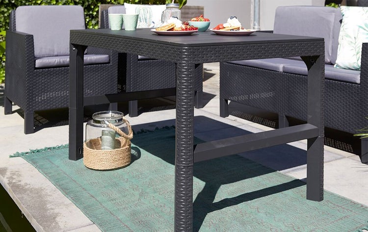 Quadratischer Gartentisch aus Polyrattan mit Gedeck und Dekoration