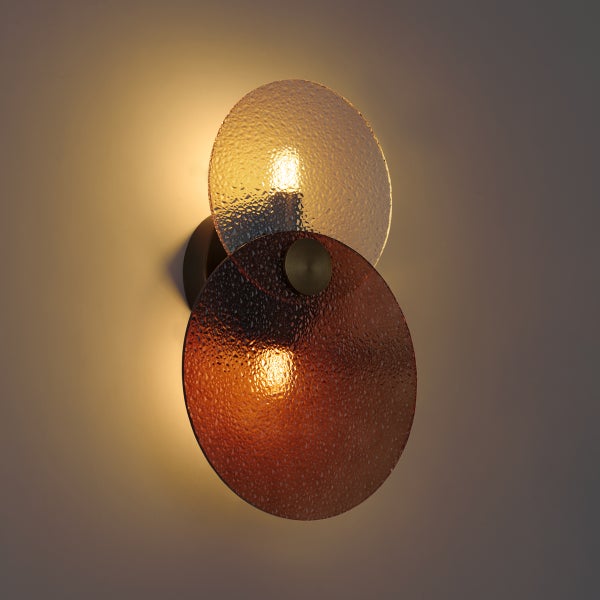 Moderne Wandleuchte mit zwei runden, strukturierten Glasscheiben für atmosphärische Beleuchtung.