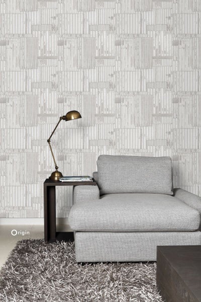 Innenraum mit hellgrauer Tapete in Holzoptik, Sessel, Teppich und Tischleuchte