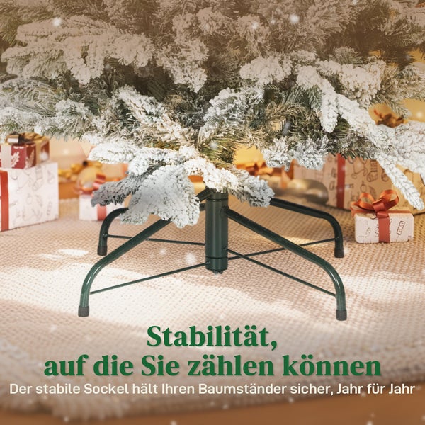 Stabiler Christbaumständer aus Metall mit vier Standfüßen unter einem beschneiten künstlichen Weihnachtsbaum mit Geschenken im Hintergrund.