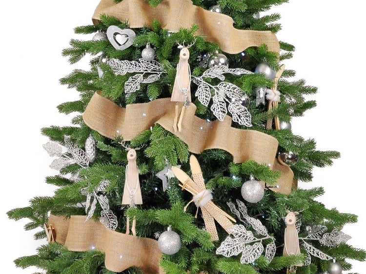 Weihnachtsbaum geschmückt mit Juteband, silbernen Kugeln, Holzfiguren von Rentieren und Miniaturskiern als weihnachtliche Dekoration.