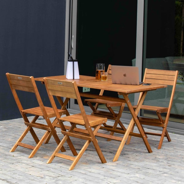 Gartenmöbel-Set aus Holz mit Tisch und vier Klappstühlen auf einer Terrasse. Organisiertes Ensemble mit Laptop und Lampe vor einer Glasfront.