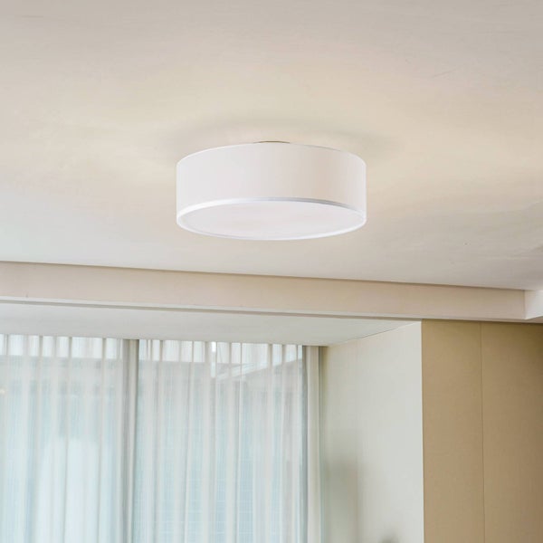 Runde Deckenleuchte mit Stoffschirm an der Zimmerdecke in einem hellen Raum.