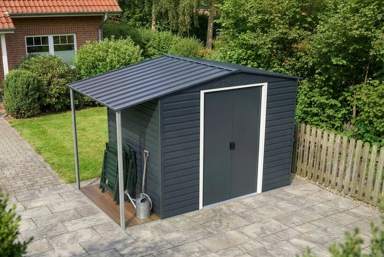 Anthrazitfarbenes Metall-Gerätehaus mit Satteldach und Schleppdach auf einer hellen Steinterrasse in einem gepflegten Garten.