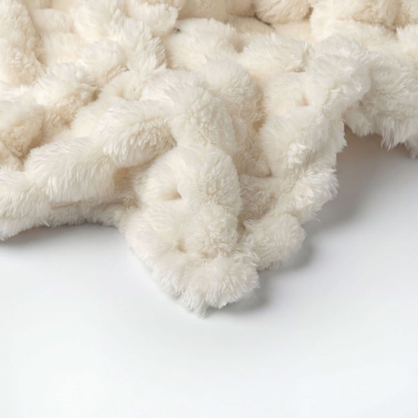 Flauschige, cremefarbene Wohndecke aus weichem Kunstfell mit strukturierter Oberfläche.