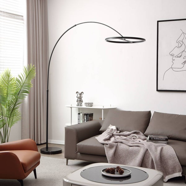 Moderne schwarze LED-Bogenlampe mit ringförmigem Kopf in einem hellen Wohnzimmer über einem grauen Sofa.