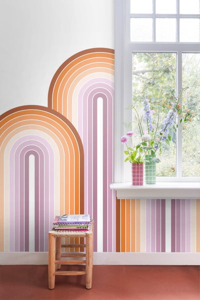 Raum mit Fenster, Holzstuhl mit Büchern und Wandgestaltung mit bunten Regenbögen und Streifen.