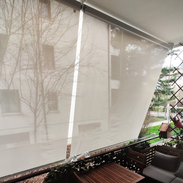 Zwei halbtransparente Senkrechtmarkisen als Sichtschutz und Sonnenschutz auf einem Balkon mit Gartenmöbeln.
