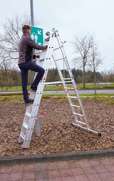 Eine Person steht auf einer Mehrzweckleiter und arbeitet an einem Schild