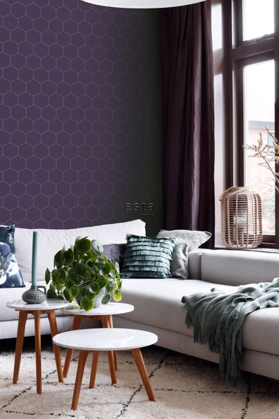 Wohnzimmer mit Couch, Couchtischen, Topfpflanze und Wandtapete mit geometrischem Muster.