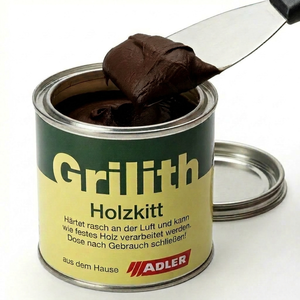 Eine geöffnete Dose Adler Grilith Holzkitt mit einem Spachtel, der dunkle Holzpaste entnimmt.