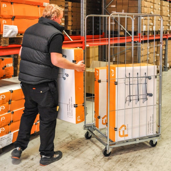 Mann schiebt Rollwagen mit Waren im Lager