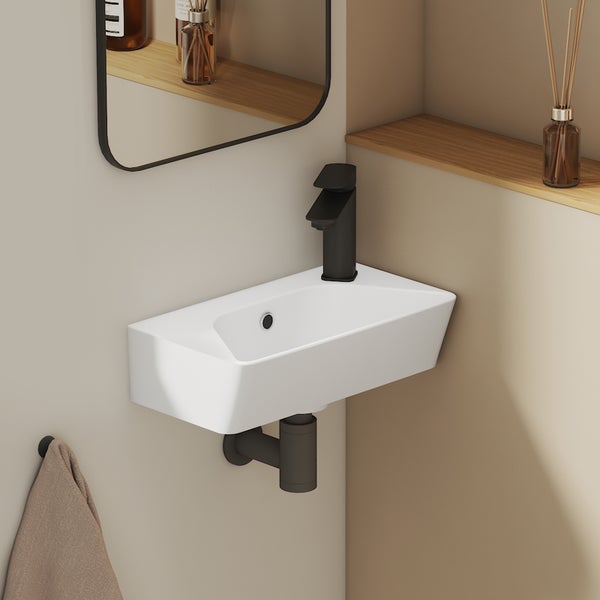 Modernes Wand-Handwaschbecken aus Keramik mit schwarzer Armatur und passendem Siphon in einem minimalistischen Badezimmer.