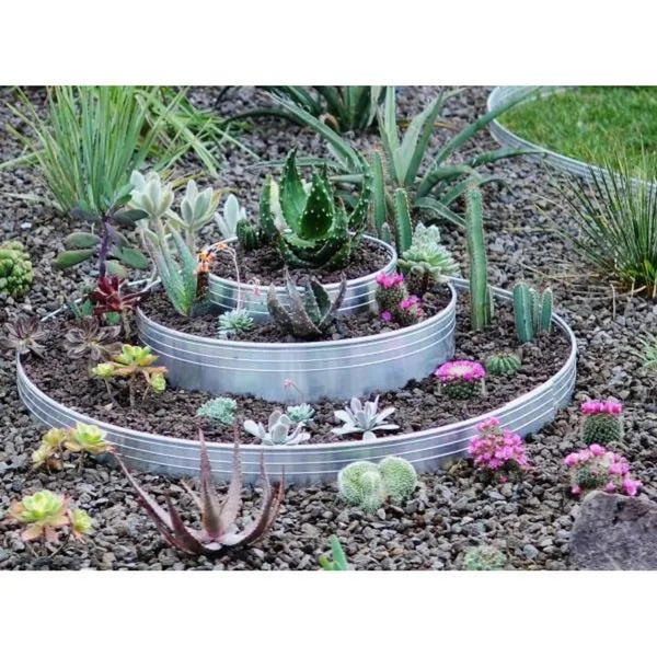 Mehrstufiges Hochbeet aus verzinktem Stahlblech mit Sukkulenten und Kakteen bepflanzt in einem mit Kieselsteinen dekorierten Gartenbeet.