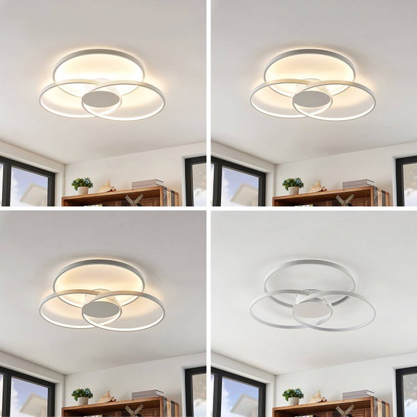 Moderne LED-Deckenleuchte mit drei überlappenden Ringen in verschiedenen Helligkeitsstufen in einem hellen Raum mit Holzregal.