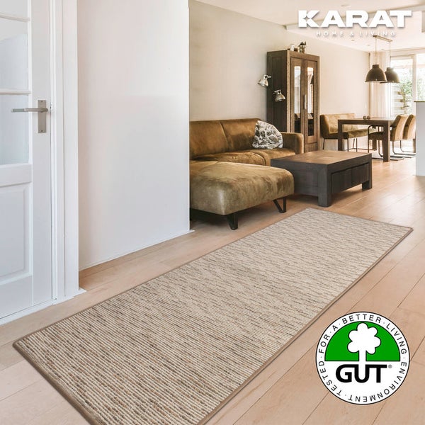 Gestreifter Läufer in hellem Wohnzimmer mit Sofa und Holzfußboden. Karat Home und Living Logo. Gut Siegel für umweltfreundliche Teppiche.
