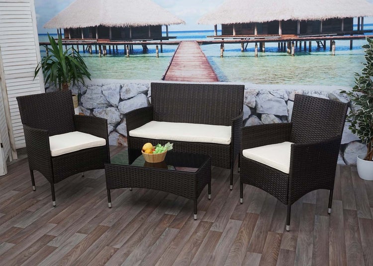 Vierteiliges Gartenmöbel-Set aus Polyrattan bestehend aus einem Sofa, zwei Sesseln und einem Couchtisch mit Glasplatte inklusive Sitzkissen.