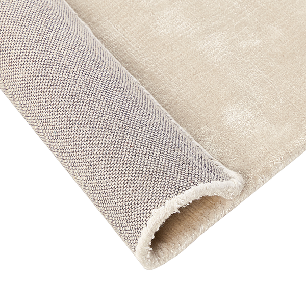 Beiger weicher Hochflor-Teppich mit samtiger Oberfläche und geketteltem Rand.