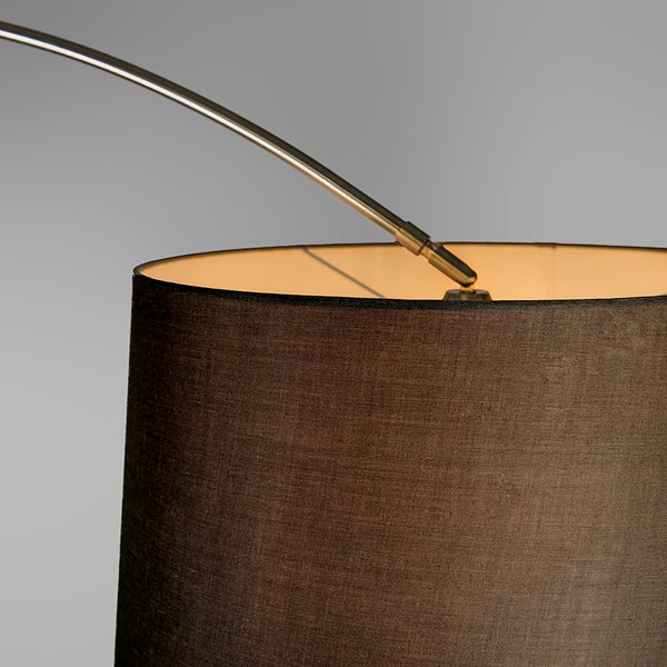 Detailaufnahme einer Stehlampe mit einem Lampenschirm aus Stoff und einem gebogenen Metallarm.