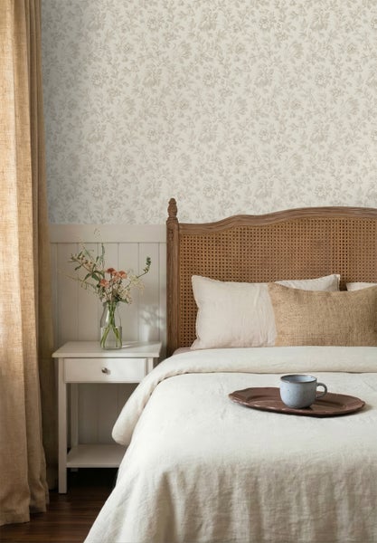 Schlafzimmer mit Blumentapete, weißer Wandvertäfelung, Holzbett mit Rattan-Kopfteil und einem weißen Nachttisch.