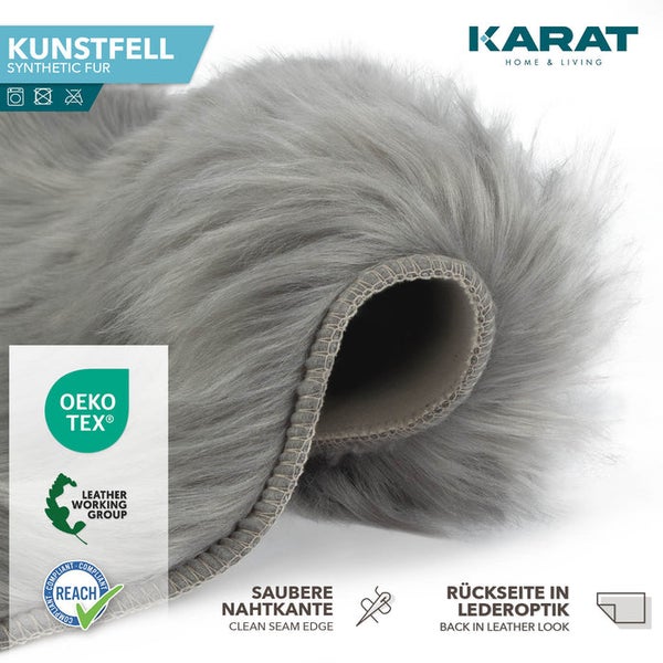 Karat Home and Living Logo. Grauer Kunstfell-Teppich, saubere Nahtkante, Lederoptik-Rückseite, OEKO-TEX, REACH und Leather Working Group zertifiziert.