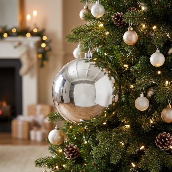 Weihnachtsbaum geschmückt mit glänzenden Weihnachtskugeln in verschiedenen Größen und Tannenzapfen, beleuchtet durch eine Lichterkette.