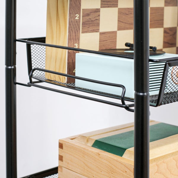 Detailansicht eines schwarzen Metallregals mit Schachbrett, Spielkonsole und Holzkiste