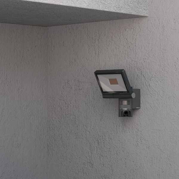 Steinel LED-Strahler mit integrierter Kamera und Bewegungsmelder an einer strukturierten Außenwand montiert.