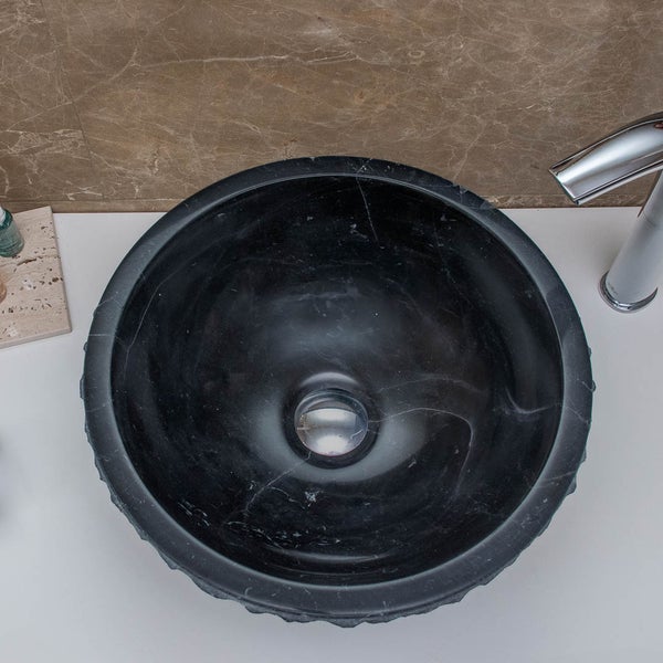 Rundes Aufsatzwaschbecken aus schwarzem Marmor mit weißer Maserung, montiert auf einer Waschtischplatte neben einer verchromten Armatur.