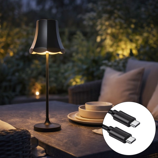 Schwarze, wiederaufladbare LED-Tischleuchte mit gewelltem Schirm auf einem Gartentisch inklusive USB-C-Ladekabel.