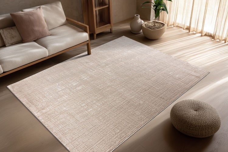 Rechteckiger Teppich mit geometrischem Strukturmuster in einem hellen Wohnzimmer mit Sofa und Holzmöbeln.