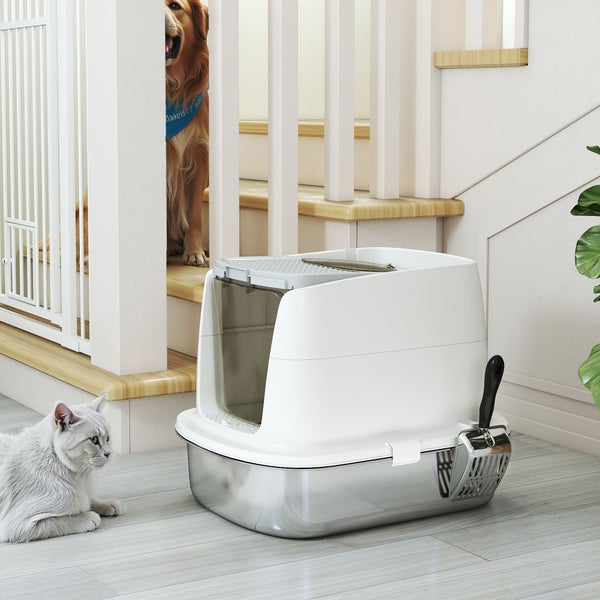 Katzentoilette mit Edelstahlwanne und weißem Gehäuse neben einer Treppe im Innenbereich, inklusive Streuschaufel und Katze.