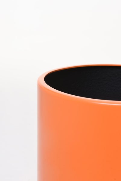 Detailaufnahme eines zylindrischen orangefarbenen Blumentopfs mit glatter Oberfläche und dunkler Innenseite.
