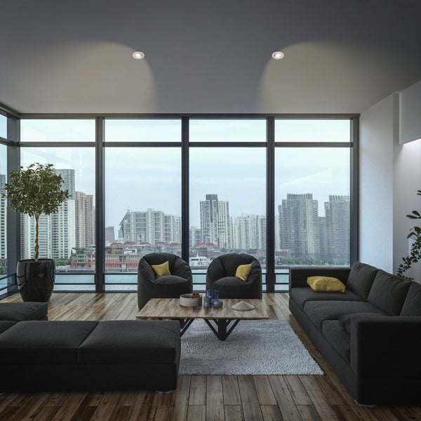 Wohnzimmer mit Sofa, Sesseln und Stadtblick durch Panoramafenster