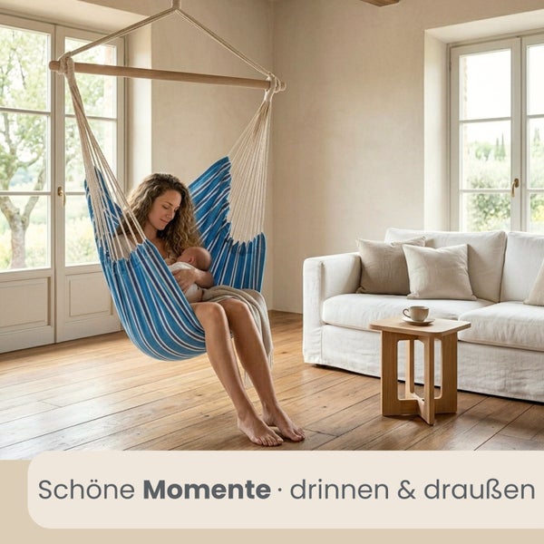 Gestreifter Hängesessel aus Baumwolle mit Holzstab in einem hellen Wohnzimmer mit Parkettboden und Sofa.