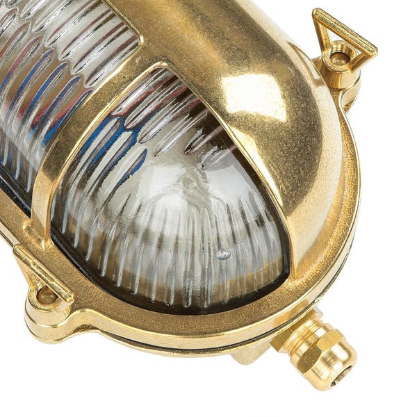 Nahaufnahme einer goldenen Schiffslampe mit klarem, geriffeltem Glas