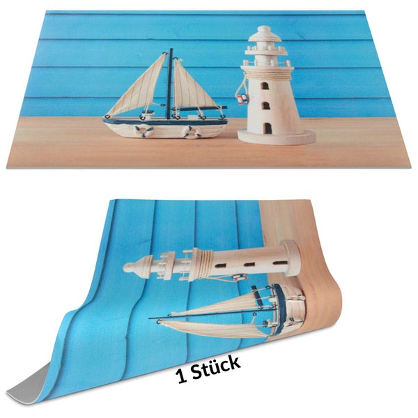 Küchenrückwand mit maritimem Motiv aus Segelboot und Leuchtturm vor einer blauen Holzwand, ein Stück.