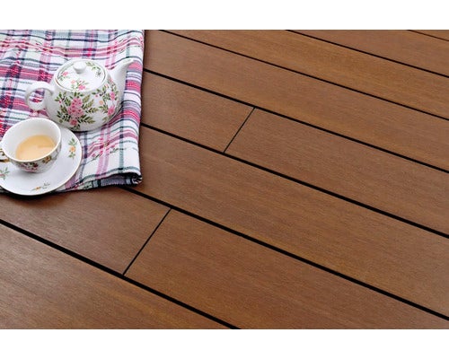 Braune Terrassendielen in Holzoptik mit feiner Maserung, darauf ein Teegeschirr mit Blumenmuster auf einem karierten Tuch.