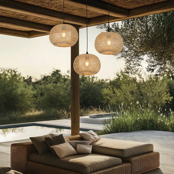 Drei runde Hängeleuchten aus Korbgeflecht unter einer Holzpergola im Außenbereich mit Loungebett und Pool.